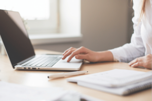 Frau, die an einem Tisch vor einem Laptop sitzt